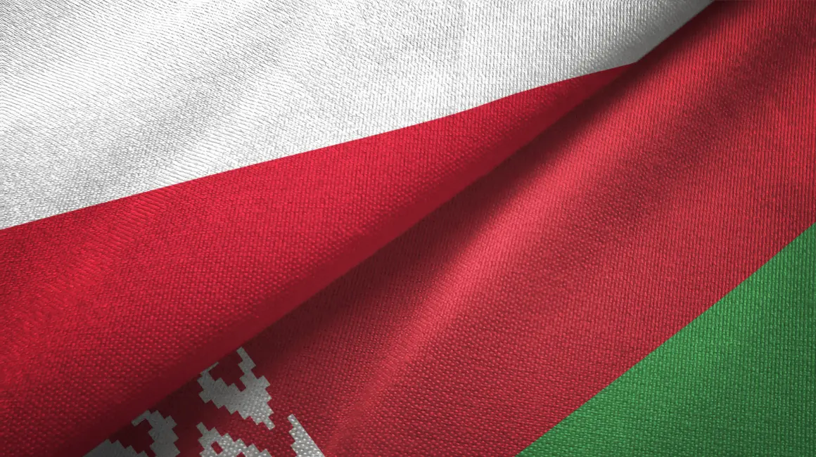 Zbliżenie na fragmenty flag Polski i Białorusi, splecione razem w symbolicznym geście współpracy